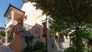 Un edificio a due piani con facciata in pietra, un balcone con ringhiere in metallo decorate e una scala che conduce al piano superiore.