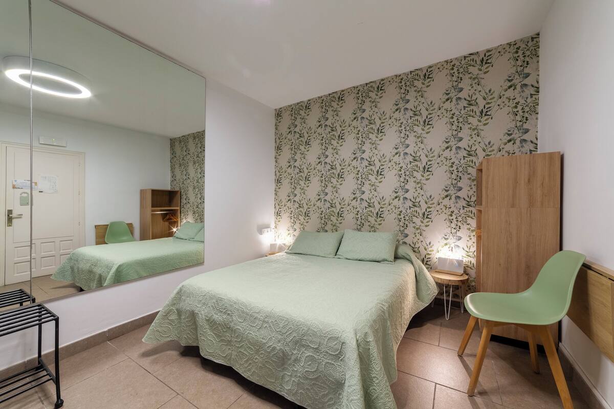 Un dormitorio con dos camas, un espejo, un armario y una silla.