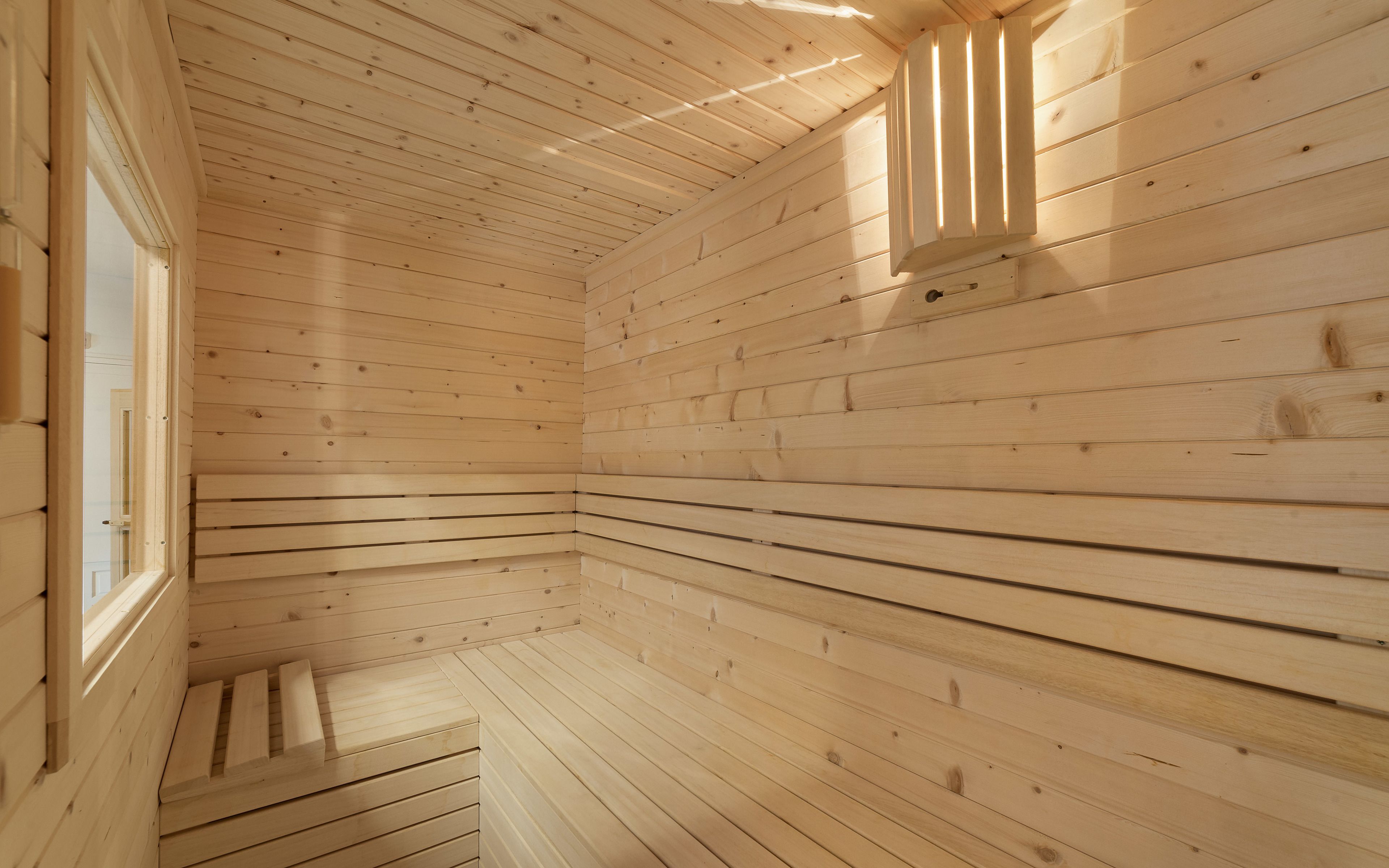 A wooden interior with a sloped ceiling and a window on the left.