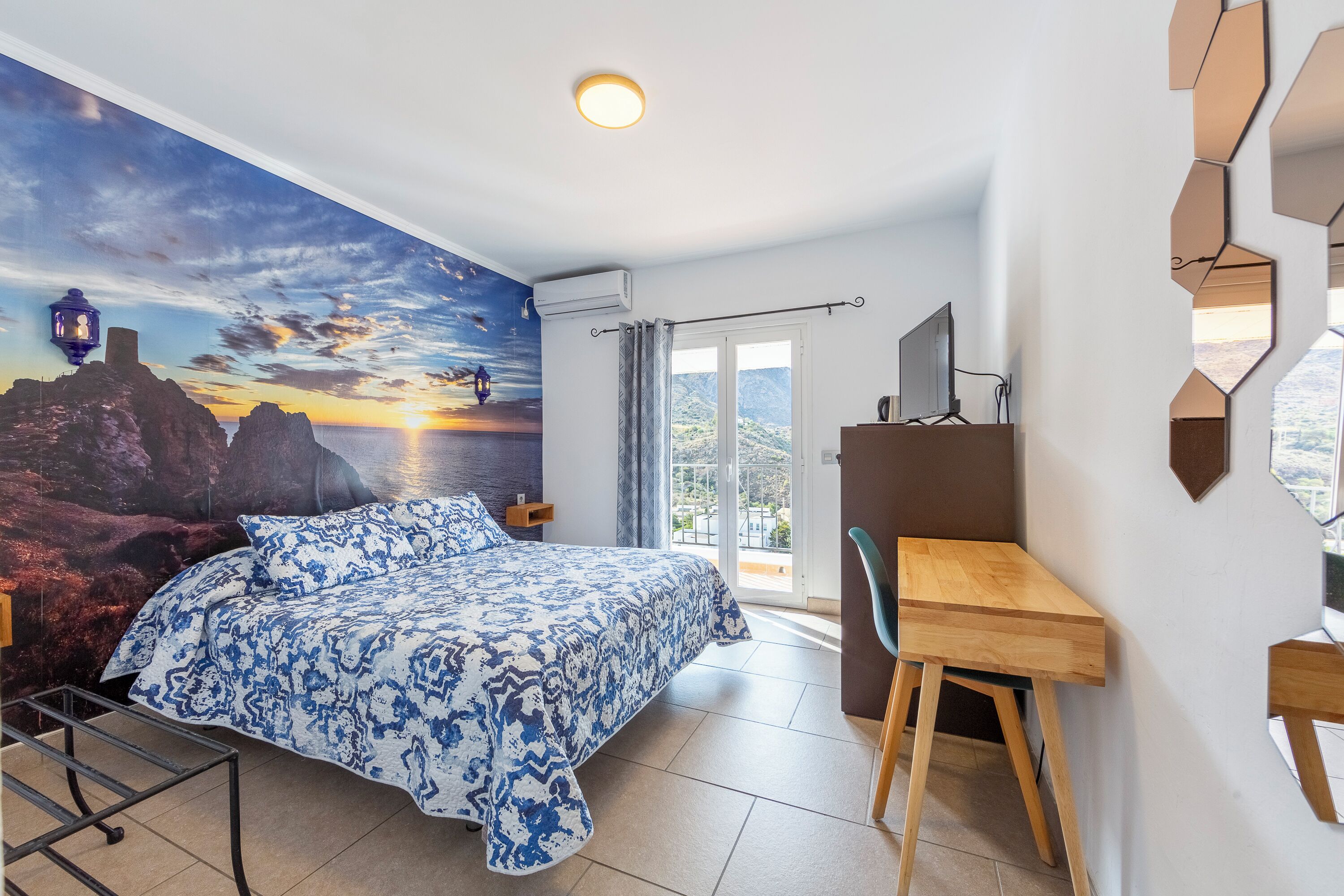 Un dormitorio con cama, escritorio y vistas al exterior.