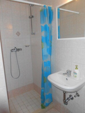 A bathroom with a shower, a sink, and a mirror.