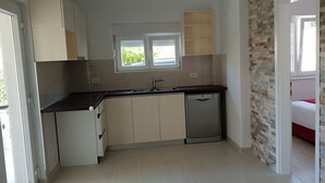 A compact kitchen with a dishwasher, a window, and a stone accent wall. - Apartments MIA Bilo 887 (Primosten)