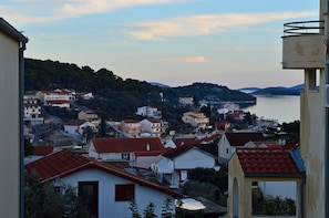 Uma cidade costeira com edifícios, um corpo d'água e colinas ao fundo.