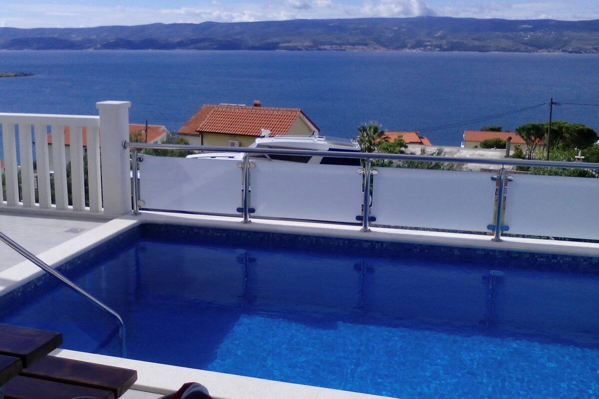 A swimming pool with a view of the sea and distant mountains.