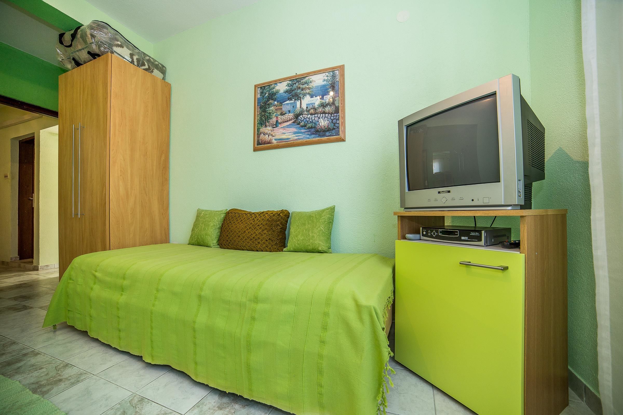 A bedroom with a bed, a television, a cabinet, and a painting on the wall.