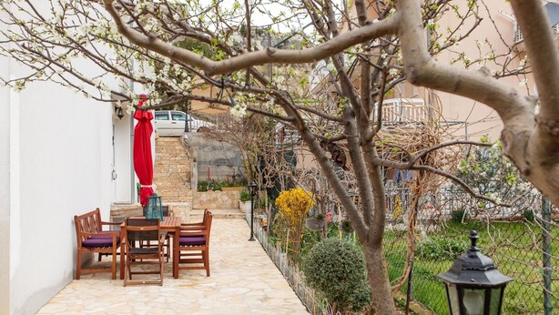 A patio with stone flooring, wooden furniture, and a red umbrella. - Apartments Villa Dane / Two Bedrooms A3 (Podstrana)