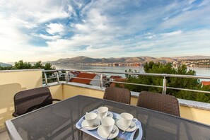 A balcony with a table set for tea, overlooking a river and hills. - Apartments Villa Luna (Okrug)