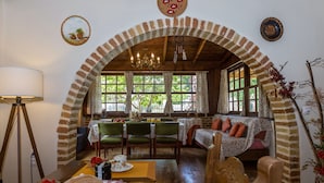 A cozy dining area with a brick arch, wooden furniture, and a view of greenery outside. - Maria's Countryside House (Corfu)