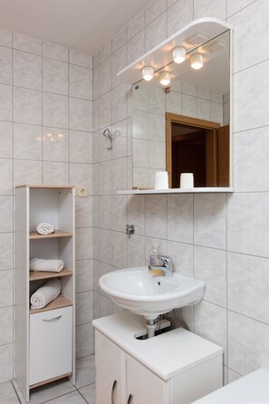 A bathroom with a white sink, a mirror, and a towel rack. - Apartments Villa Dane (Podstrana)