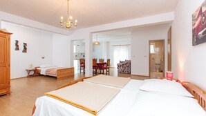 A spacious bedroom with a large bed, a wooden wardrobe, a dining area, and a bathroom visible through an open door. - Apartments Villa Dane (Podstrana)