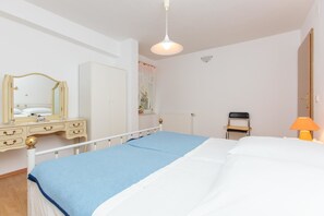 A bedroom with a bed, a dresser, a mirror, a chair, and a lamp. - Apartments Villa Dane (Podstrana)