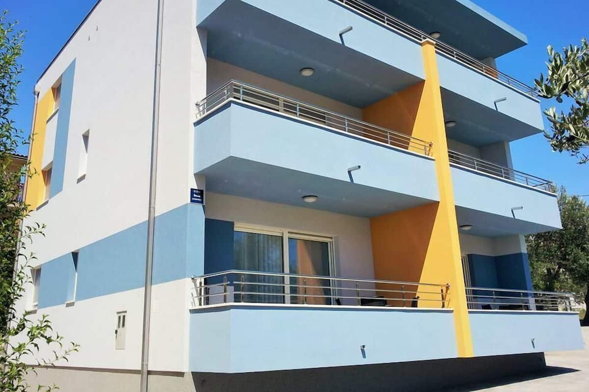 A multi-story building with balconies, a flat roof, and a clear sky.