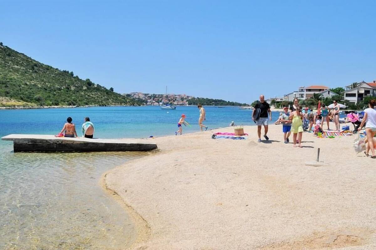 A beach with clear water, a pier, and people relaxing.