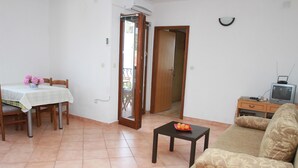 A living room with a dining table, sofa, TV, and a small table with fruit. - Apartments Sanader (Okrug)