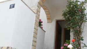 A building with a stone staircase leading to a door, a stone archway, and a sign indicating the number 16. - Apartments Sanader (Okrug)