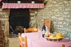 A table set with a checkered tablecloth, a bottle of wine, glasses, and a fruit basket.