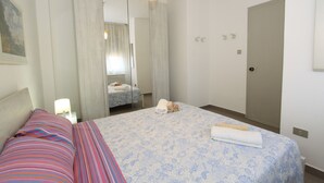 Une chambre d’hôtel avec un lit, une table de chevet, un miroir, une armoire et une porte.