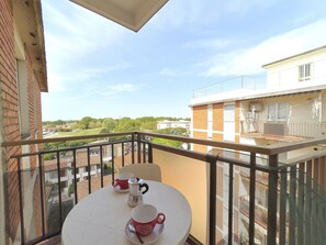 Un balcon avec une table, deux tasses et une cafetière.