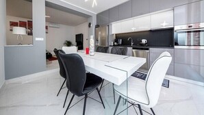 A modern kitchen with white cabinets, stainless steel appliances, and a dining area with a white table and black chairs.