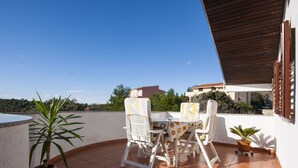 Une terrasse avec une table et des chaises, des plantes en pot et une vue sur le paysage environnant.