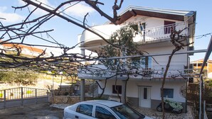 Une voiture blanche est garée devant un immeuble à deux étages doté d’un balcon.