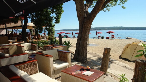 Terrasse extérieure avec vue sur la plage et la mer.