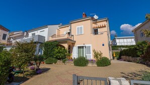 Un immeuble résidentiel doté d’une cour pavée, d’un petit jardin et d’un portail.
