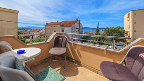Un balcon avec une chaise, une petite table et une vue sur le paysage urbain.