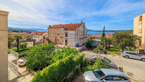 Un quartier résidentiel avec un immeuble blanc surmonté d’un toit rouge, entouré de verdure et de voitures garées.