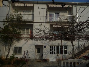 A multi-story residential building with balconies, a small garden area, and a staircase leading to an upper floor. - Apartments Konta (Kastela)