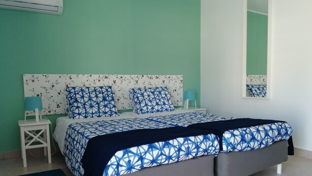 A bedroom with a bed, nightstands, a mirror, and a wall-mounted air conditioner.