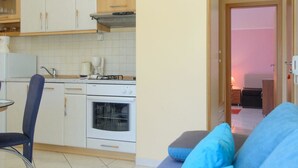 A compact living space with a kitchenette, a dining area, and a sofa with blue cushions. - Apartments Anton (Marina)