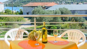 A balcony with a table set for two, a bottle of wine, and a bowl of grapes. - Apartments Anton (Marina)
