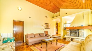 A living room with a wooden ceiling, a sofa, a coffee table, and a fireplace. - Apartment Belušić / Three Bedrooms A1 (Fazana)