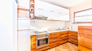 A modern kitchen with white cabinets, a built-in oven, and a stainless steel range hood. - Apartment Belušić / Three Bedrooms A1 (Fazana)