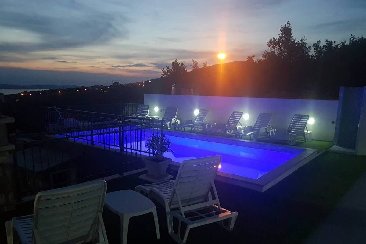 Ein Außenpoolbereich mit Liegestühlen und einem Sonnenuntergang im Hintergrund.