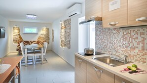 A modern kitchen with a stone accent wall, a built-in stove, and a tiled backsplash. - Apartments Salčinović (Medulin)