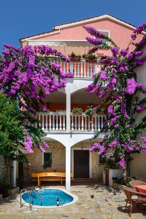 Un bâtiment à deux étages doté d’un balcon, d’une piscine et d’un espace extérieur aménagé pour s’asseoir.
