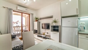 En moderne stue med sofa, fjernsyn og spisebord.