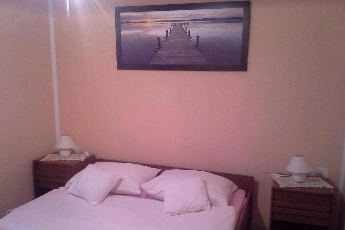 A bedroom with a bed, two bedside tables, and a framed picture on the wall.