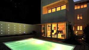 Una casa moderna con piscina, puertas de vidrio e interior bien iluminado.