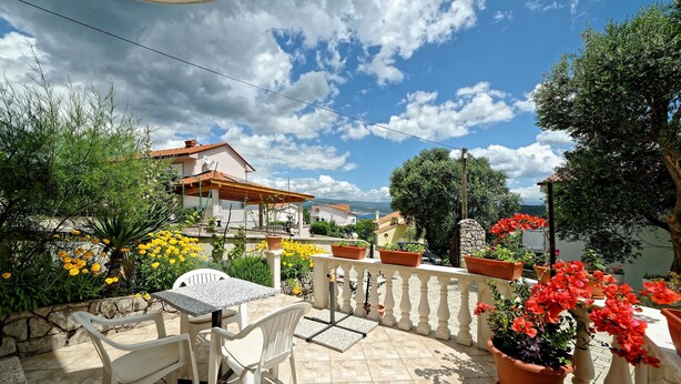A patio with a table and chairs, surrounded by potted plants and flowers. - Apartments Vedrana (Dobrinj)