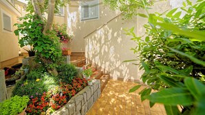 A courtyard with a stone wall, potted plants, and a tiled floor. - Apartments Vedrana (Dobrinj)
