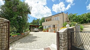 A two-story house with a paved driveway and stone walls. - Apartments Vedrana (Dobrinj)