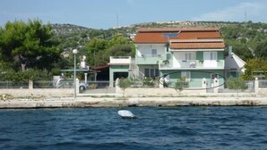A coastal building with a green facade, a red roof, and a balcony.