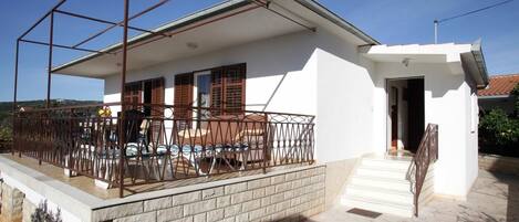 A modern house with a balcony, a swimming pool, and a small attached garage.