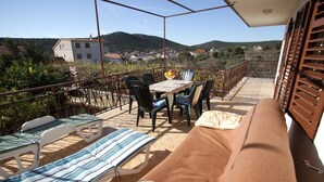 A balcony with a table and chairs, a sofa, and a view of the surrounding landscape.