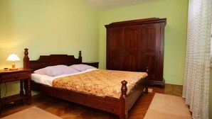 A bedroom with a wooden bed, a nightstand with a lamp, a wardrobe, and a patterned bedspread.