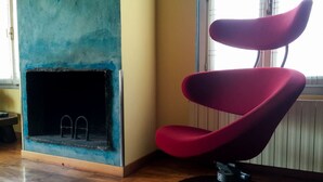 A red chair in a room with a blue wall and a fireplace. - B&B Treviglio (Treviglio)