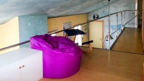 A room with a white cabinet, a purple bean bag chair, a staircase, and a door with a number sign. - B&B Treviglio (Treviglio)